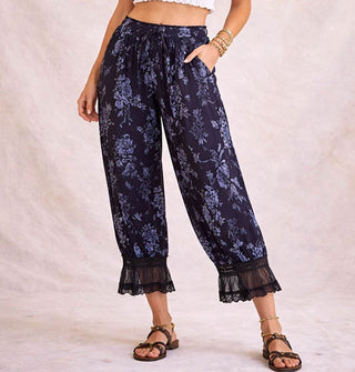 Model wears dark blue-gray pantaloons with flocked velvet floral pattern, elasticated tie waist, and lace trim
