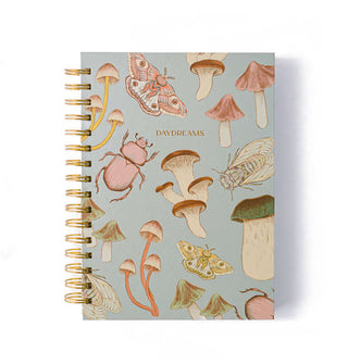 Blue notebook with gold spiral binding features illustrations of insects and mushrooms across its cover and the word, "Daydreams" printed in gold foil