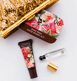 Dead Sexy Date Night Kit tin, lip tint tube, and opened eau de parfum vial spill out of a gold sequined clutch