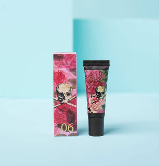 Tube of lip gloss with pink floral patterning and skull and crossbones illustration alongside its matching gift box packaging