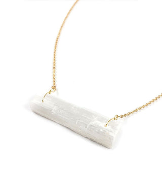 Closeup of a whitish translucent rectangular selenite stone strung at both ends from gold chain with gold wire