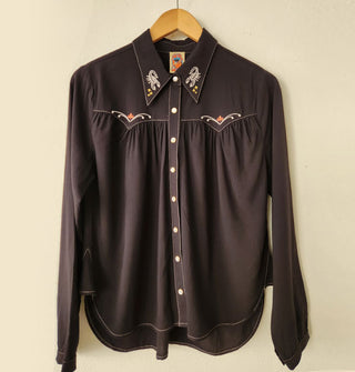Black Western-style shirt with embroidered details on the collar and front yoke points, gathering at the chest seam, white stitching, and pearl snap buttons