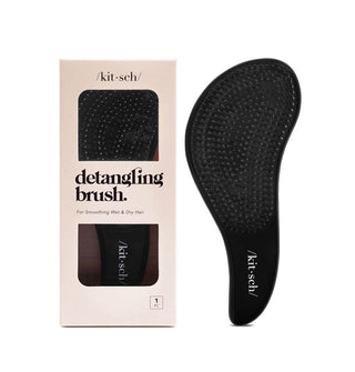 Curvy black Kitsch Detangling Brush with white logo printed on the handle is shown both inside its box packaging and removed at right of the box
