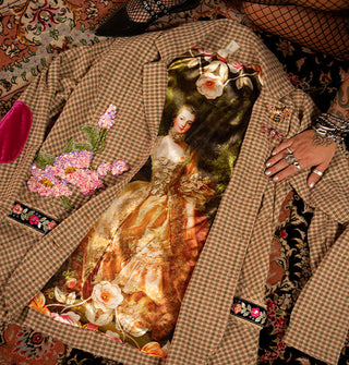 Brown and green plaid blazer lays partially open on a rug next to seated model in fishnets, revealing the Portrait of Madame de Pompadour by François Boucher on satin lining the inside