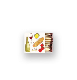 A partially opened white matchbox with watercolor wine bottle, wine glass, lemon, baguette, cheese, and tomatoes designs contains wooden matchsticks with brown tips