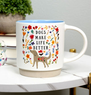Dogs Make Life Better floral coffee mug rests on a marbled tabletop with books and a potted plant