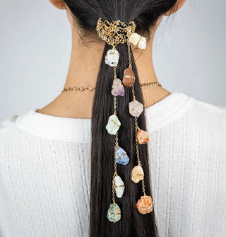Model wears two dangling, crystal-embellished chains attached to a gold wire-wrapped hair tie in a low ponytail