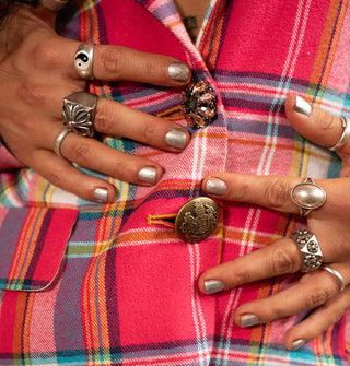 Closeup of crystal and metal button closures on a pink and multicolored plaid blazer with model's hands