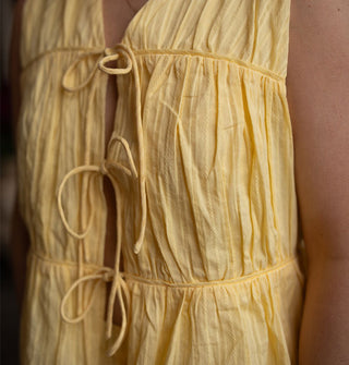 Model wears a yellow open-front sleeveless top with three tie closures