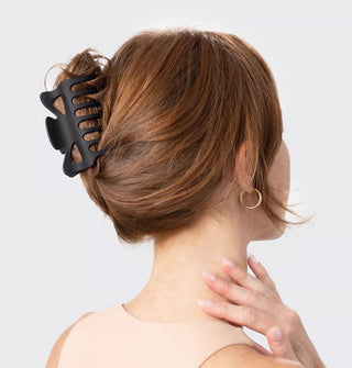 Model wears a matte black claw clip in a loose twist updo