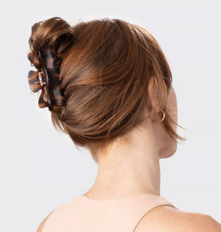 Model wears a matte brown tortoise claw clip in a loose twist updo