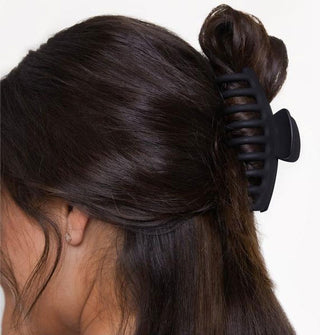 Model wears an extra-large matte black claw clip in a half-up twist hairstyle