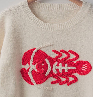 Closeup of bright red embroidered lobster detail with thick border and white accents