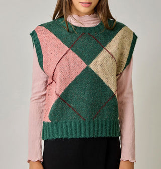 Model wears a green, beige, pink, and burgundy argyle sweater vest with cap sleeves and ribbed hems over a pink lettuce-edged mock turtleneck