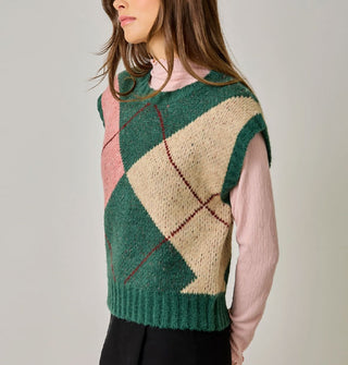 Model wears a green, beige, pink, and burgundy argyle sweater vest with cap sleeves and ribbed hems over a pink lettuce-edged mock turtleneck