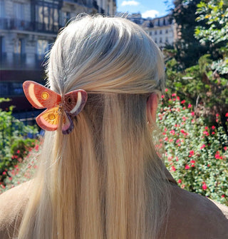 Model wears a butterfly claw clip in a partially swept-back hairstyle