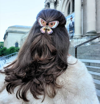 Model wears a butterfly hair clip in a partially swept-back style