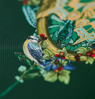 Closeup of bird, berries, and butterfly illustration on a dark green notebook cover