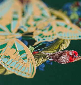 Closeup of bird and butterflies illustration on a dark green notebook cover