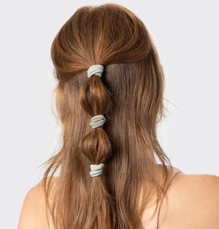 Model wears three light green cloth hair elastics in a partial ponytail