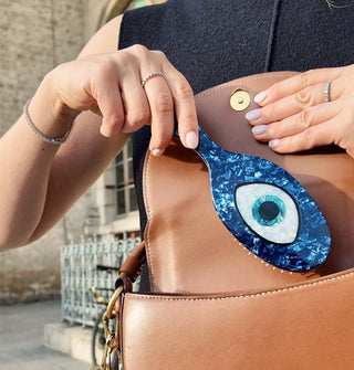 Model pulls a blue evil eye hairbrush from brown leather handbag