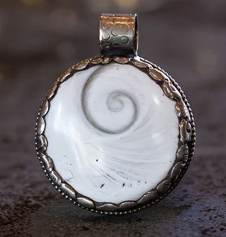 Round white spiral seashell necklace pendant set in ornate scalloped silver border with rounded top bail
