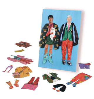 Partial contents from the Fearless Fashion Magnetic Dolls kit includes two dressed dolls on a blue card and several scattered clothing and accessory pieces