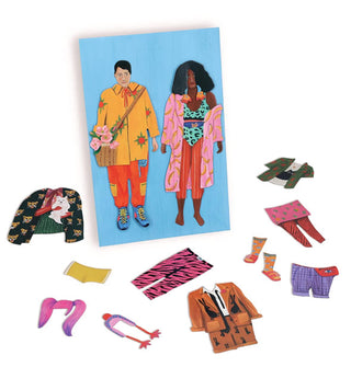 Partial contents from the Fearless Fashion Magnetic Dolls kit includes two dressed dolls on a blue card and several scattered clothing and accessory pieces