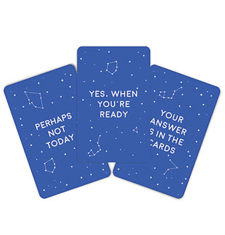 Three blue fanned-out fortune telling cards with stars and constellations on them say, "Perhaps not today," "Yes, when you're ready," and "Your answer is in the cards"