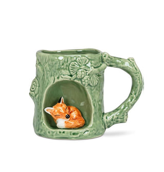 Green mug with rustic texture and tree branch designs features a circular alcove with a red fox figurine inside