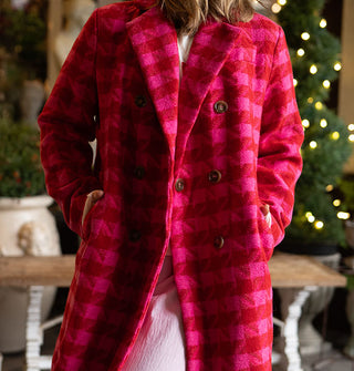 Model wears a double-breasted pink and red houndstooth coat