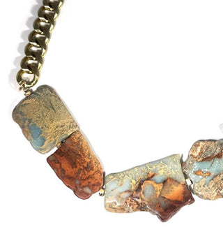 Natural jasper stones are strung on thick gold-toned curb chain