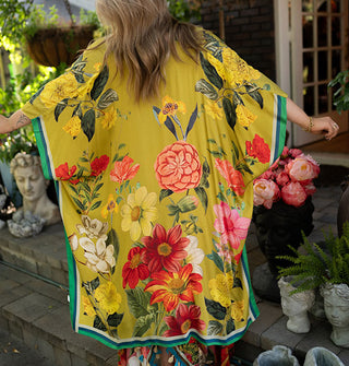 Model wears a long olive-chartreuse kimono-style robe with large floral print and contrast edge stripes