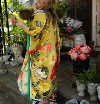 Model wears a long olive-chartreuse kimono-style robe with large floral print and contrast edge stripes