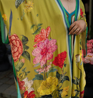 Model wears a long olive-chartreuse kimono-style robe with large floral print and contrast edge stripes