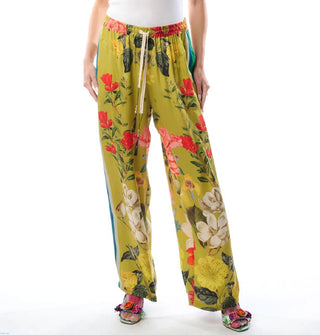 Model wears wide-legged chartreuse pants with a large floral print and an elastic waistband with ties