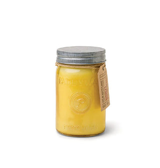 Candle jar filled with yellow wax and topped with a tin lid is hung with a brown label and filled with yellow candle wax