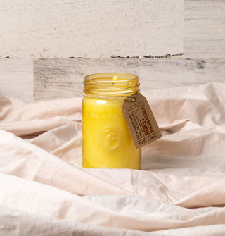 Lit Fresh Meyer Lemon jar candle on folds of linen against a whitewashed wood backdrop