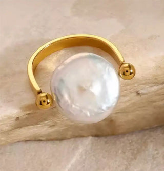 Horseshoe-shaped gold ring with a rounded pearl set between two ball band ends