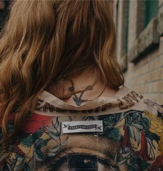 Closeup of the Market of Stars label sewn onto the back of a colorful robe worn by a model in front of a brick building