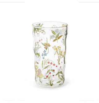 Clear drinking glass with slightly ribbed body shape features all-over delicate floral designs