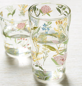 Clear drinking glasses, one tall and one short, each with a slightly ribbed body shape, feature all-over delicate floral designs