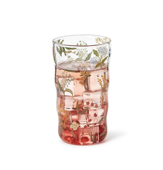 Clear drinking glass with slightly ribbed body shape features all-over delicate floral designs and holds an iced pinkish-red beverage