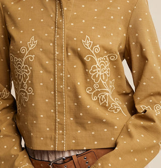 Model wears an olive green button-down shirt with white dot pattern and floral embroidery