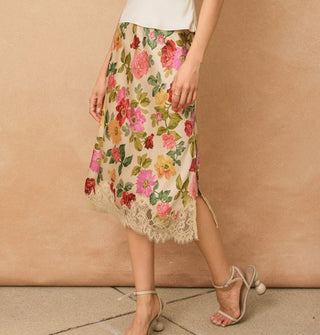 Model wears a knee-length floral-patterned skirt with lace hem and side slit