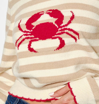 Closeup of the red crab design on a beige and cream colored sweater with red scalloped edges