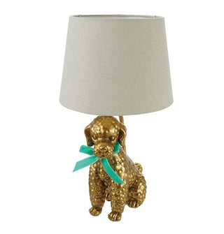 Lamp with white shade and a gold base shaped to resemble a poodle wearing a blue bow