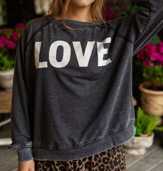 Model wears a dark gray distressed-effect sweatshirt that says, "LOVE" in large white letters