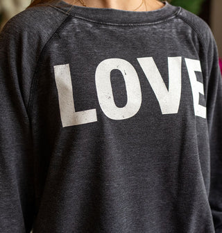 Model wears a dark gray distressed-effect sweatshirt that says, "LOVE" in large white letters