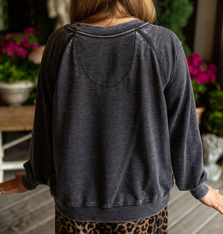 Model with back turned to camera wears a dark gray distressed-effect sweatshirt